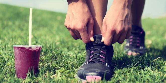 an athlete tying their shoes before running, with a beetroot smoothie