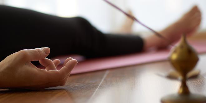 a woman in the yogic corpse pose with incense