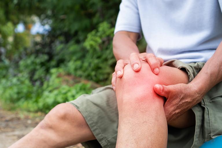 an older hiker grabbing his knee in pain