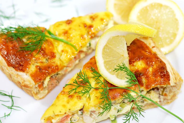 two slices of quiche, toped with sprigs of dill and a lemon wedge