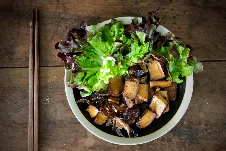 a bowl of stir-fried mushrooms and tofu, garnished